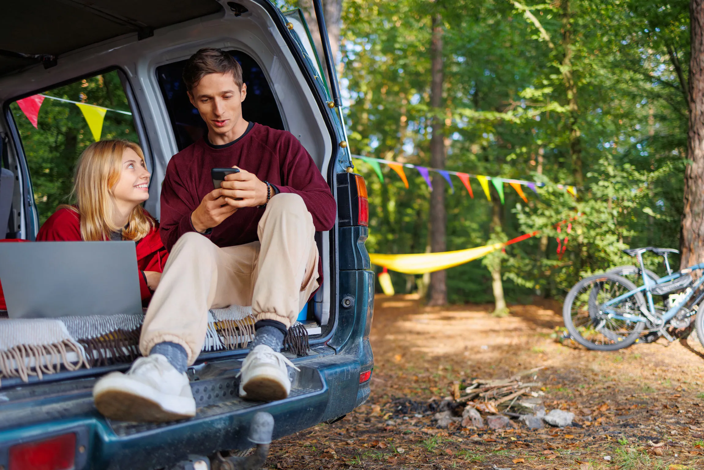 A couple siting in a car in nature using mobile banking and online banking.